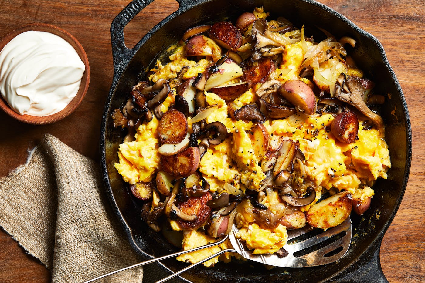 Scrambled eggs with sauteed mushrooms and onion in a Lodge cast iron pan with sour cream on the side.