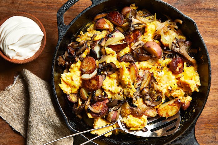 Scrambled eggs with sauteed mushrooms and onion in a Lodge cast iron pan with sour cream on the side.