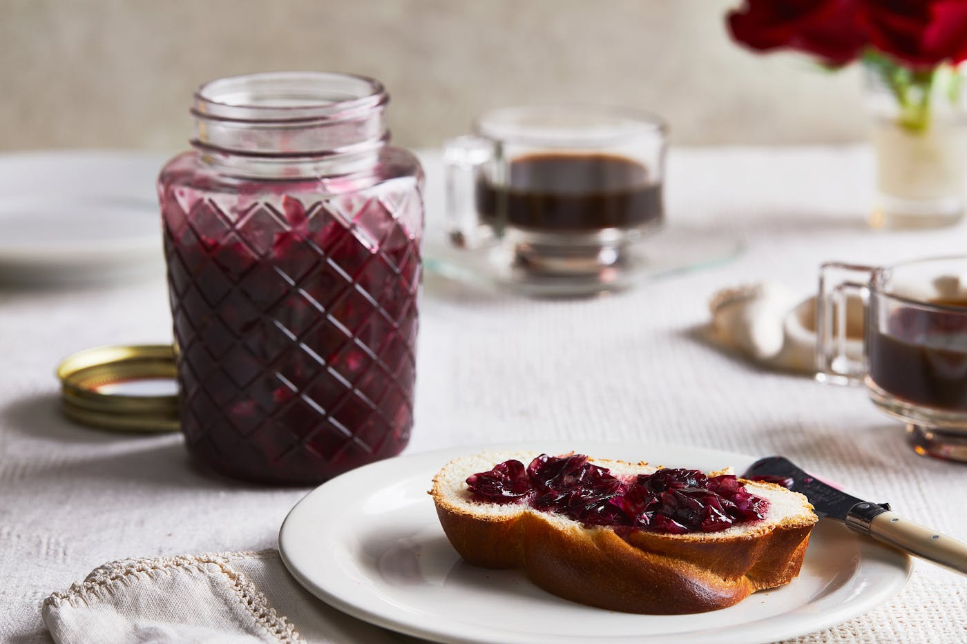 A slice of challah on a plate, spread with rose jam. 