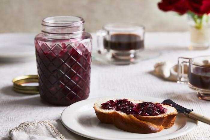 A slice of challah on a plate, spread with rose jam.