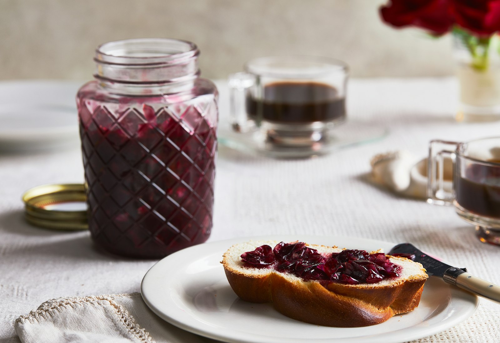 A slice of challah on a plate, spread with rose jam.