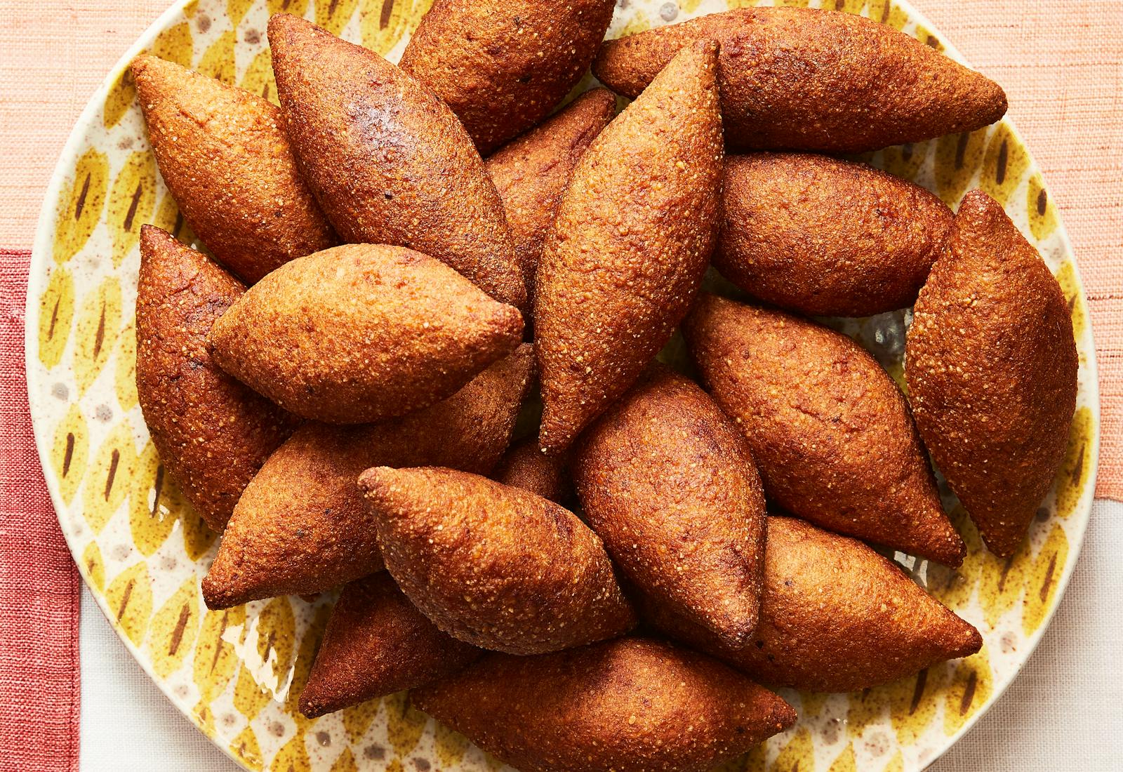 Pile of fried kibbeh on yellow graphic dish.