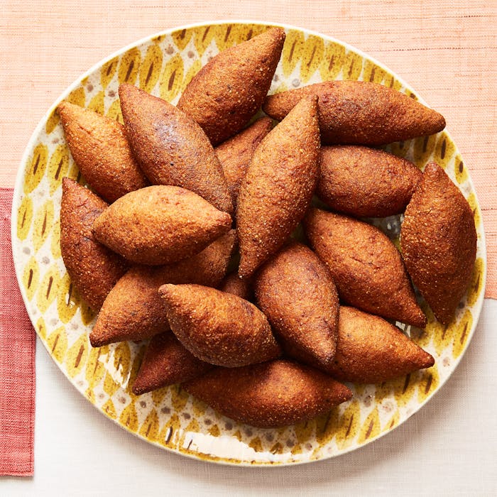 Pile of fried kibbeh on yellow graphic dish.