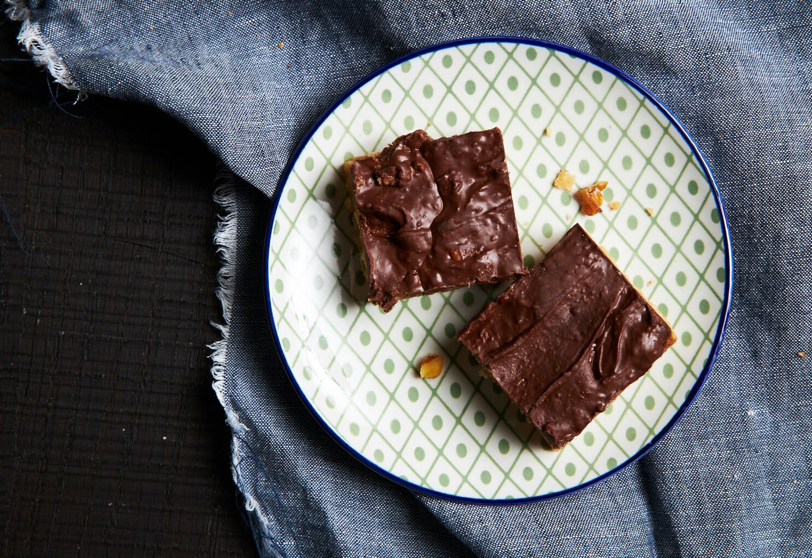 Turtle cookies on green patterned dish atop grey cloth.