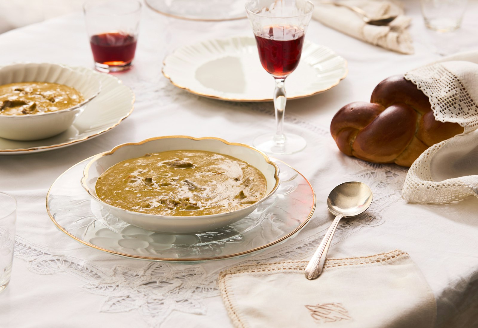 Bowls with split pea soup, glasses with red wine and challa