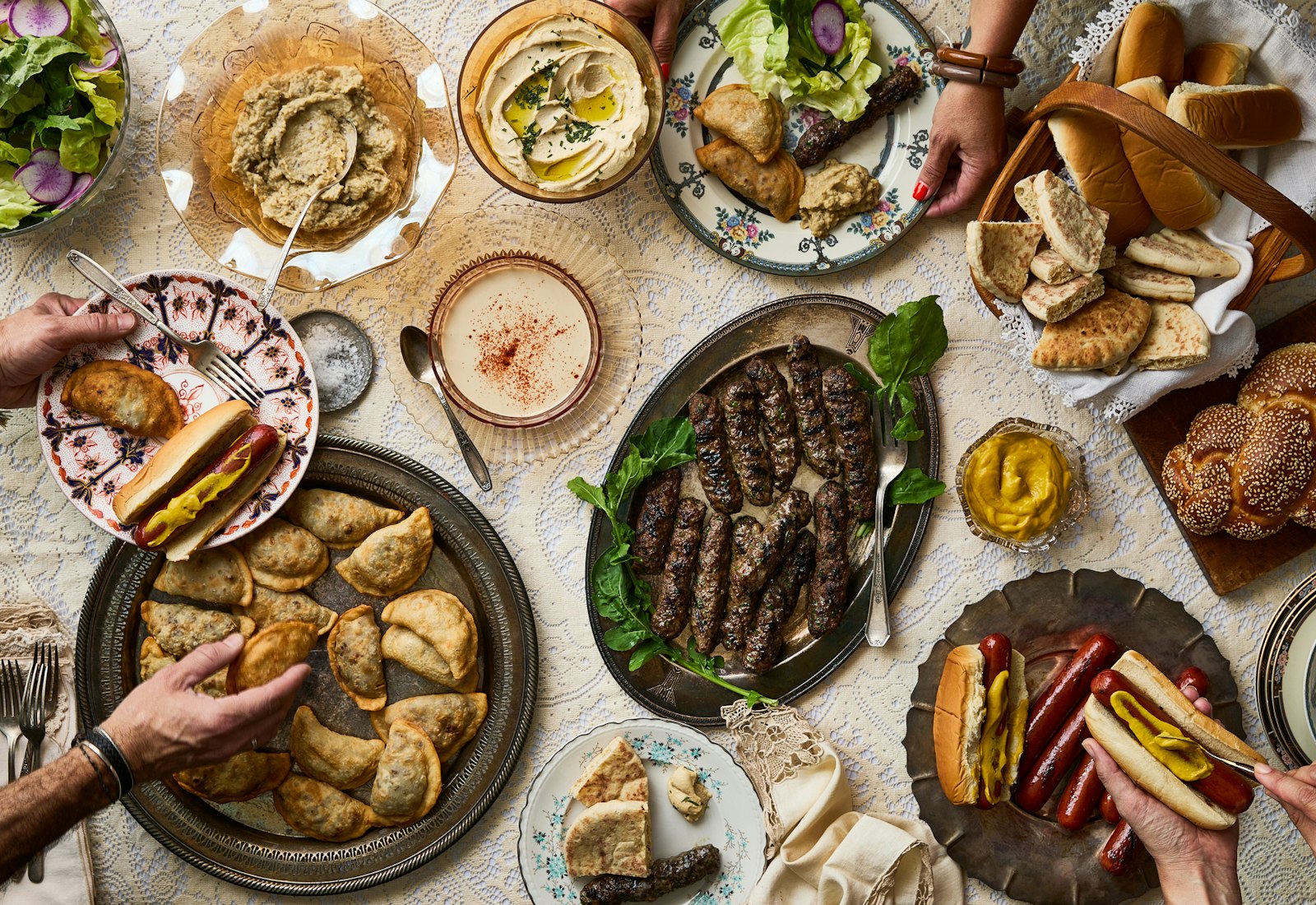 Platters with kebabs, sambousak, tahini, and hot dogs.