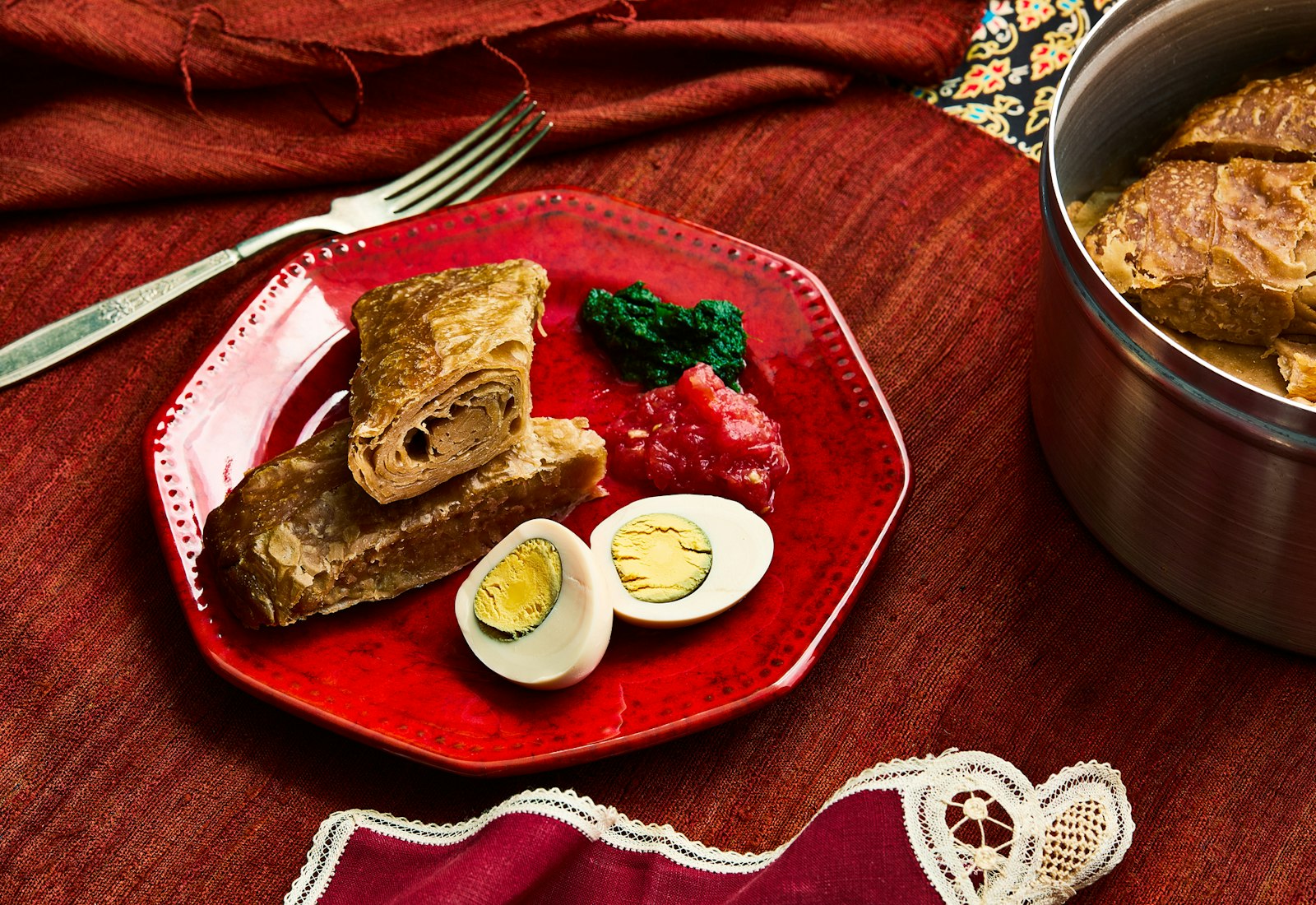 Plate of jachnun, grated tomato, slow-cooked egg and schug