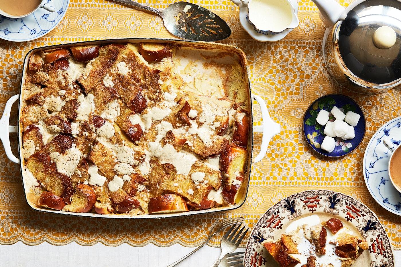 Challah bread pudding alongside cold heavy cream and coffee.
