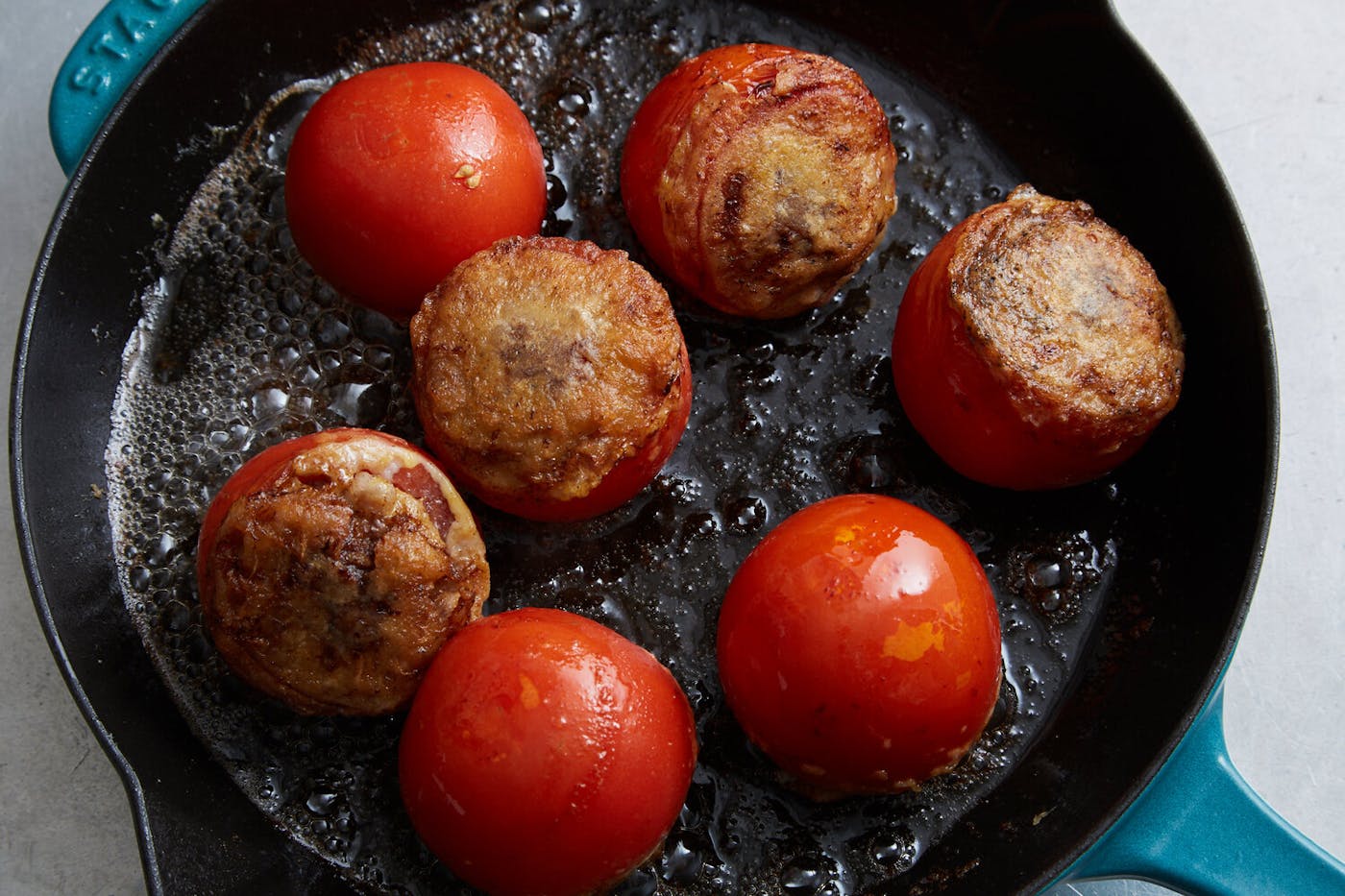 Tomatoes reinvades cooking on blue enameled cast iron skillet.