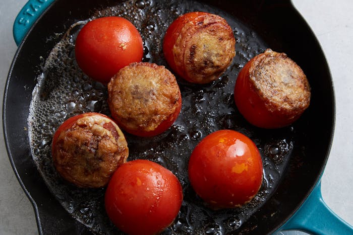 Tomatoes reinvades cooking on blue enameled cast iron skillet.