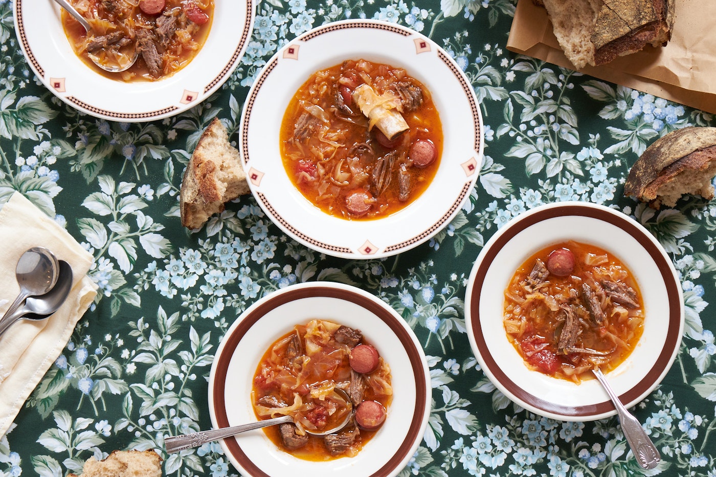 Four bowls of cabbage short rib soup on tabletop.