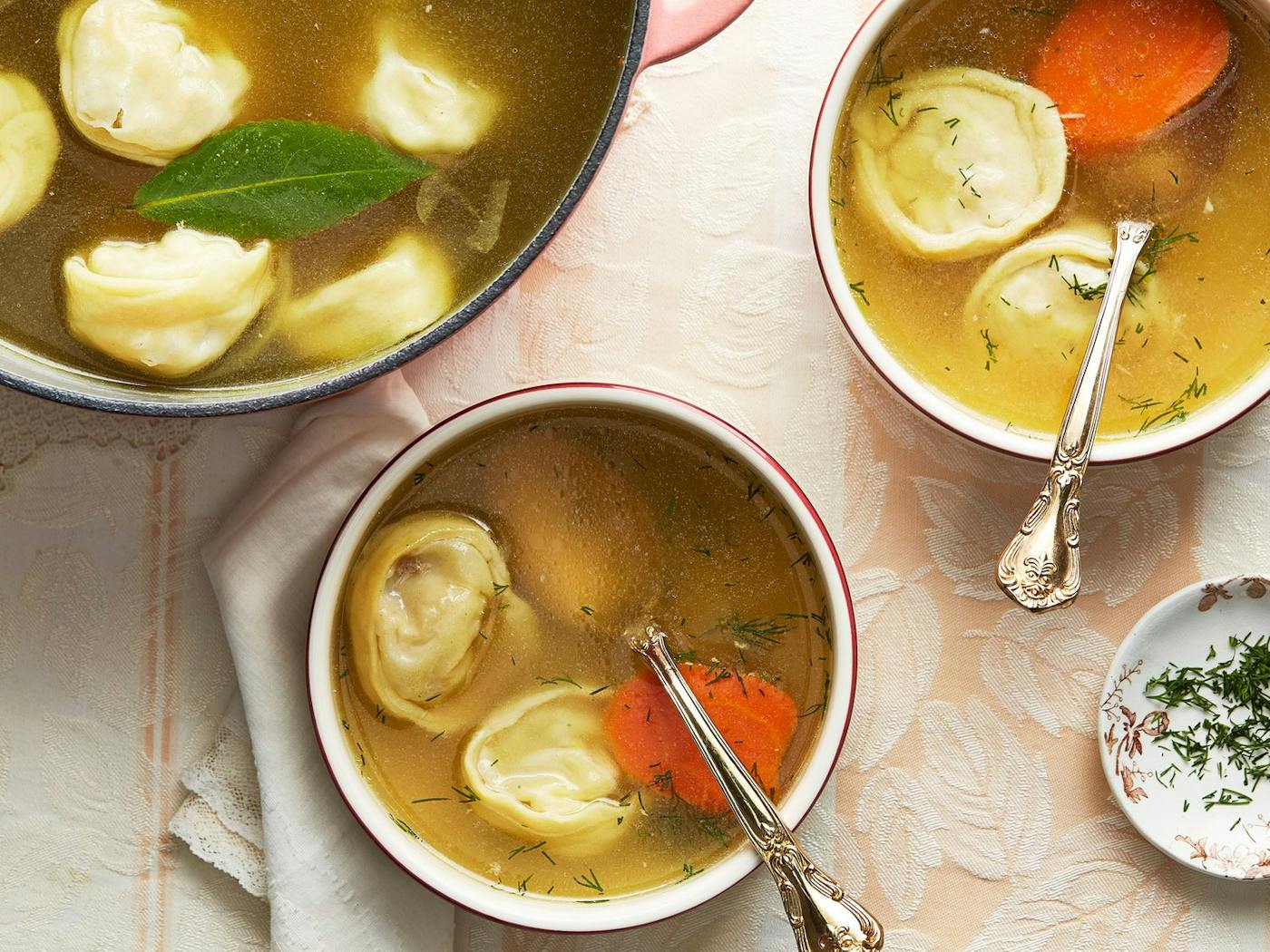 Pot of soup with two bowls and a dish of fresh dill.