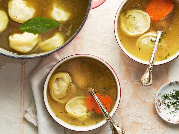 Pot of soup with two bowls and a dish of fresh dill.