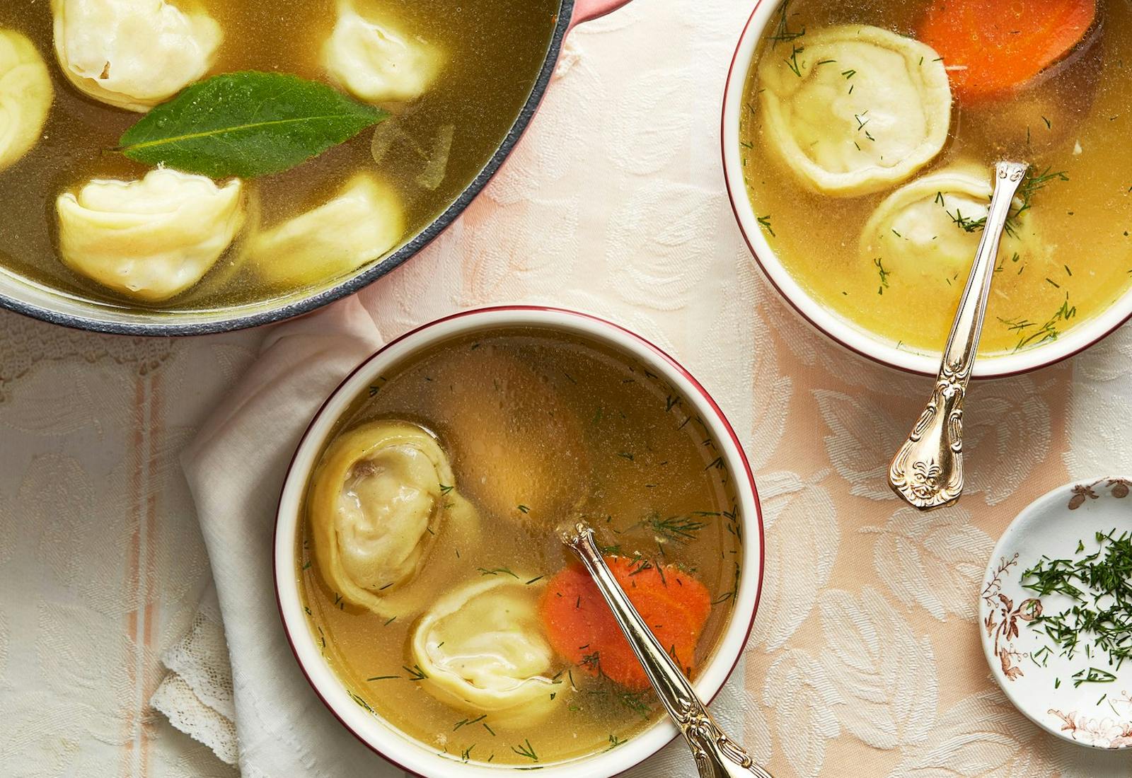 Pot of soup with two bowls and a dish of fresh dill.