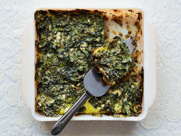 Spinach fritada in white casserole dish with pie server.