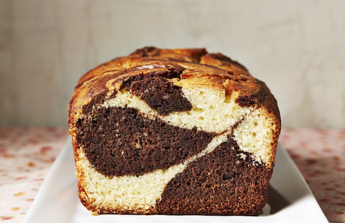 Coconut marble loaf cut in half on white plate.
