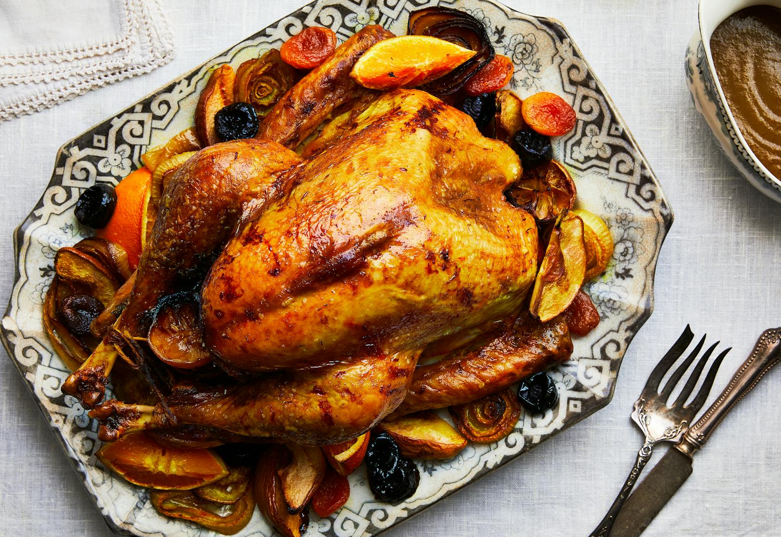 Roast turkey on serving platter atop white linen tablecloth. 