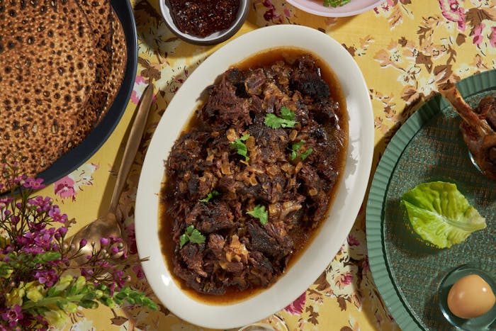 Braised beef cheeks with cilantro, round challah, fresh flowers and passover plate.