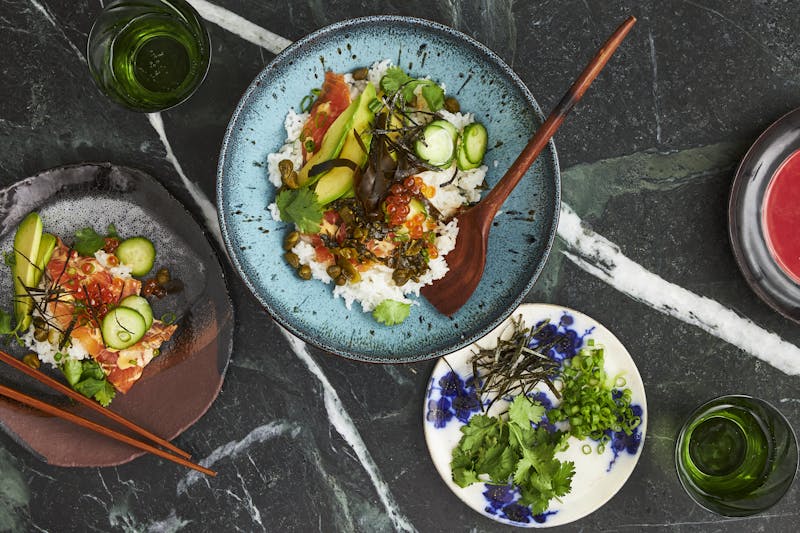 Lox bowl alongside dish of garnishes.