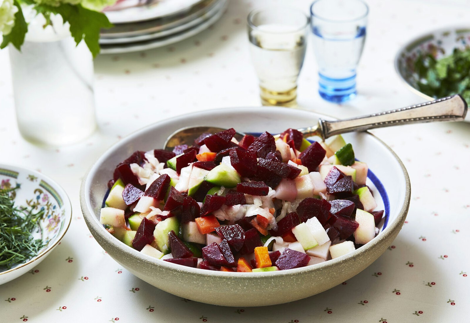 Vinaigrette in large bowl, bowls of herbs, glasses of vodka, and fresh flowers.