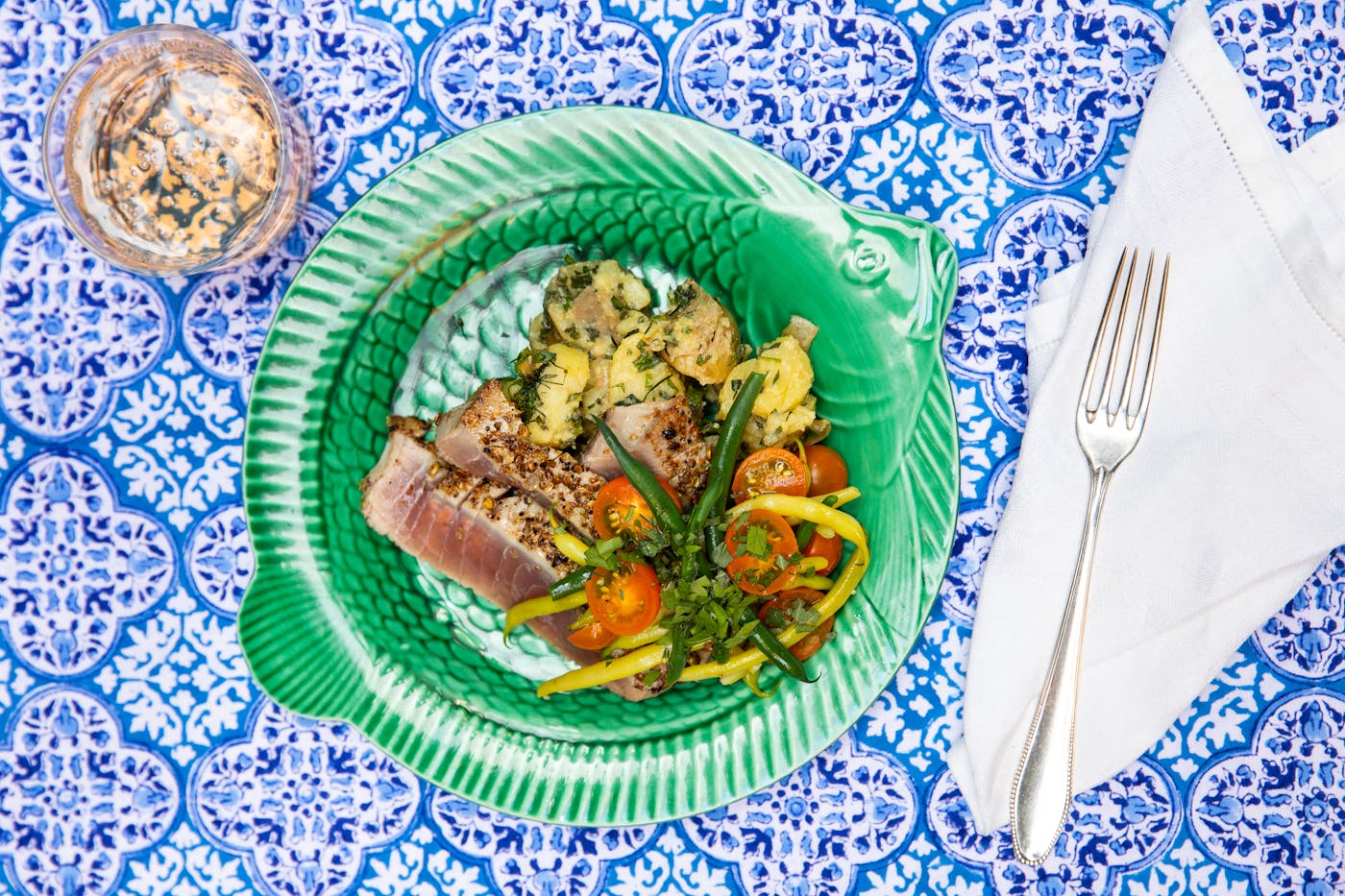 Seared spiced tuna atop blue tablecloth.