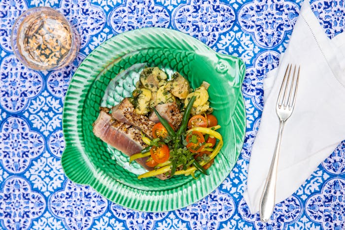 Seared spiced tuna atop blue tablecloth.