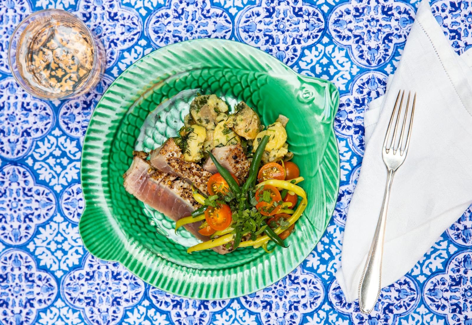 Seared spiced tuna atop blue tablecloth.