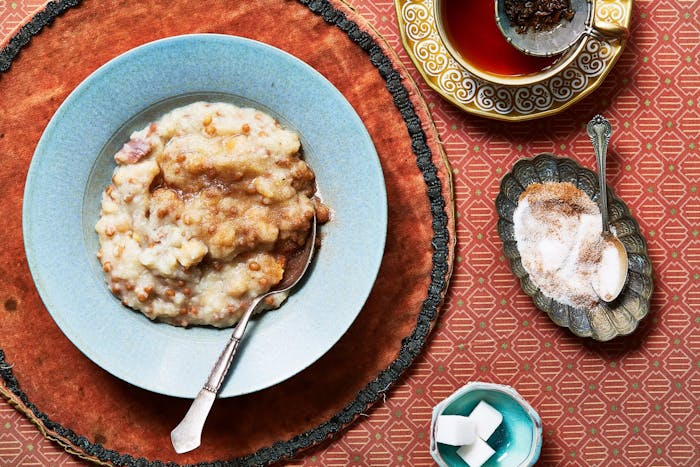 Halim sprinkled with sugar and cinnamon and hot tea, atop red patterned cloths.
