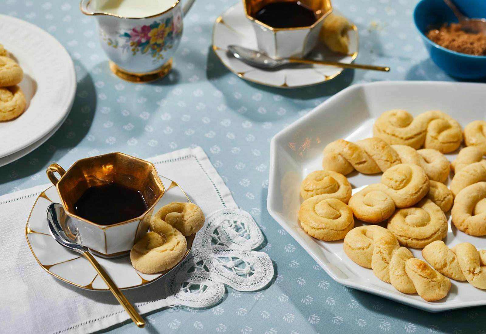 Cookies on white platter, small dishes with tea, cream.