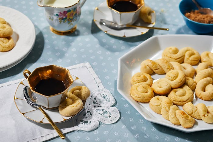 Cookies on white platter, small dishes with tea, cream.