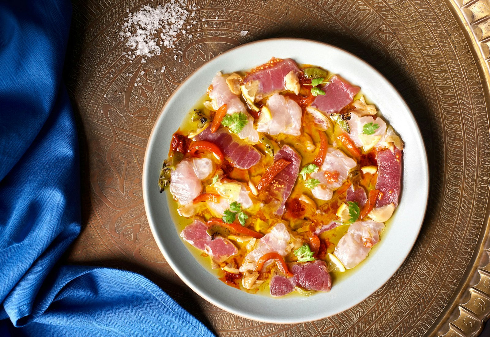Spicy Moroccan fish crudo atop metal platter with sprinkle of coarse salt.