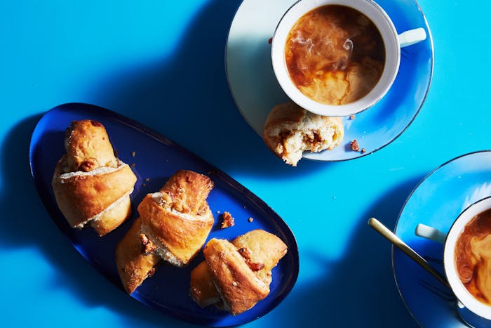 Butter horns on blue plates with mugs of milky coffee.