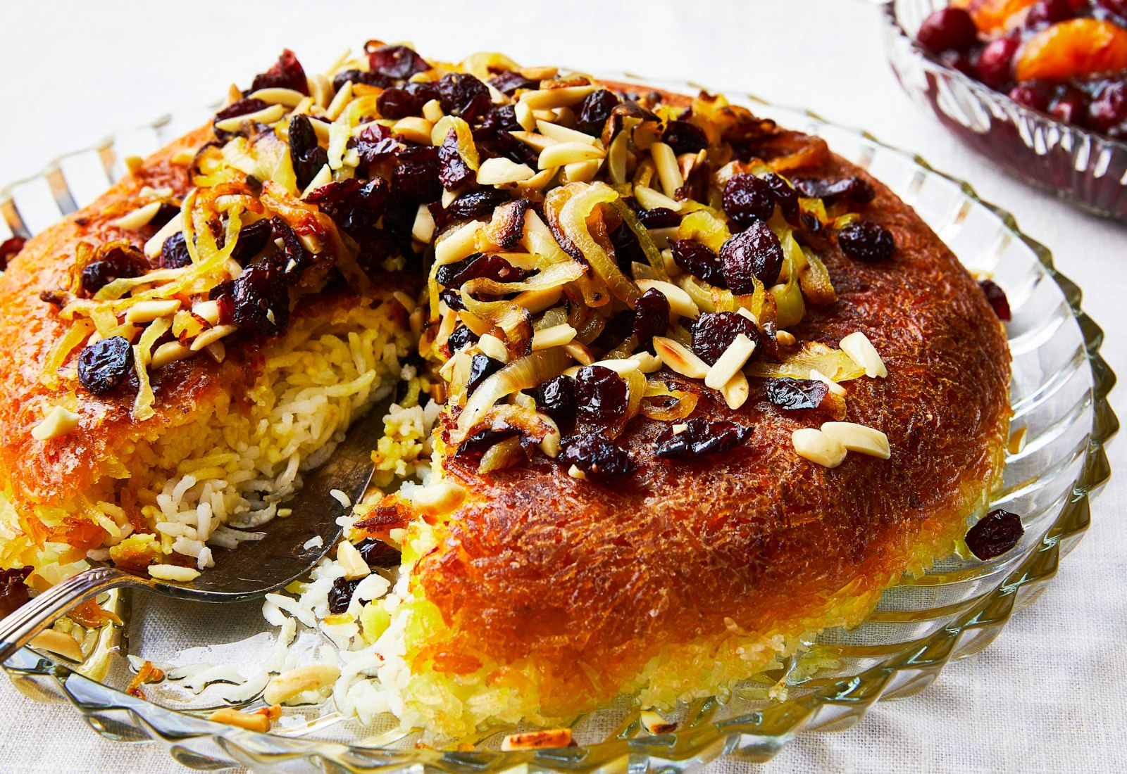 Tahdig on clear glass serving platter with one slice removed.