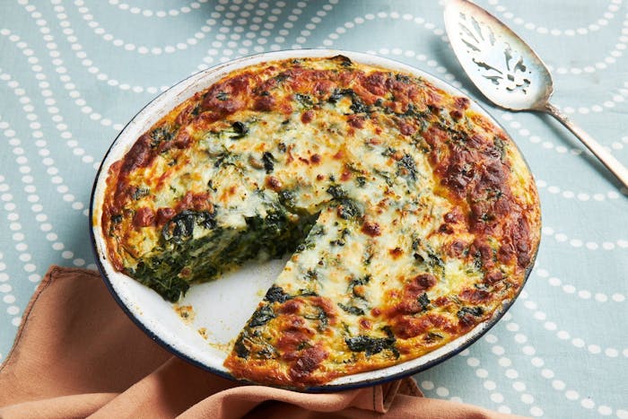 Spinach and cheese jibon in white dish atop blue tablecloth.
