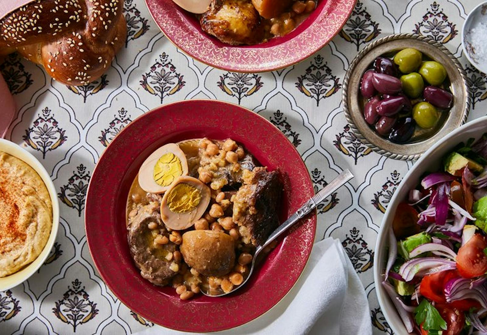 Cholent with sides of green salad, olives, hummus and challah.