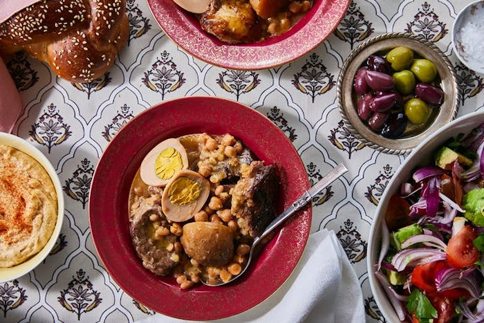 Cholent with sides of green salad, olives, hummus and challah.