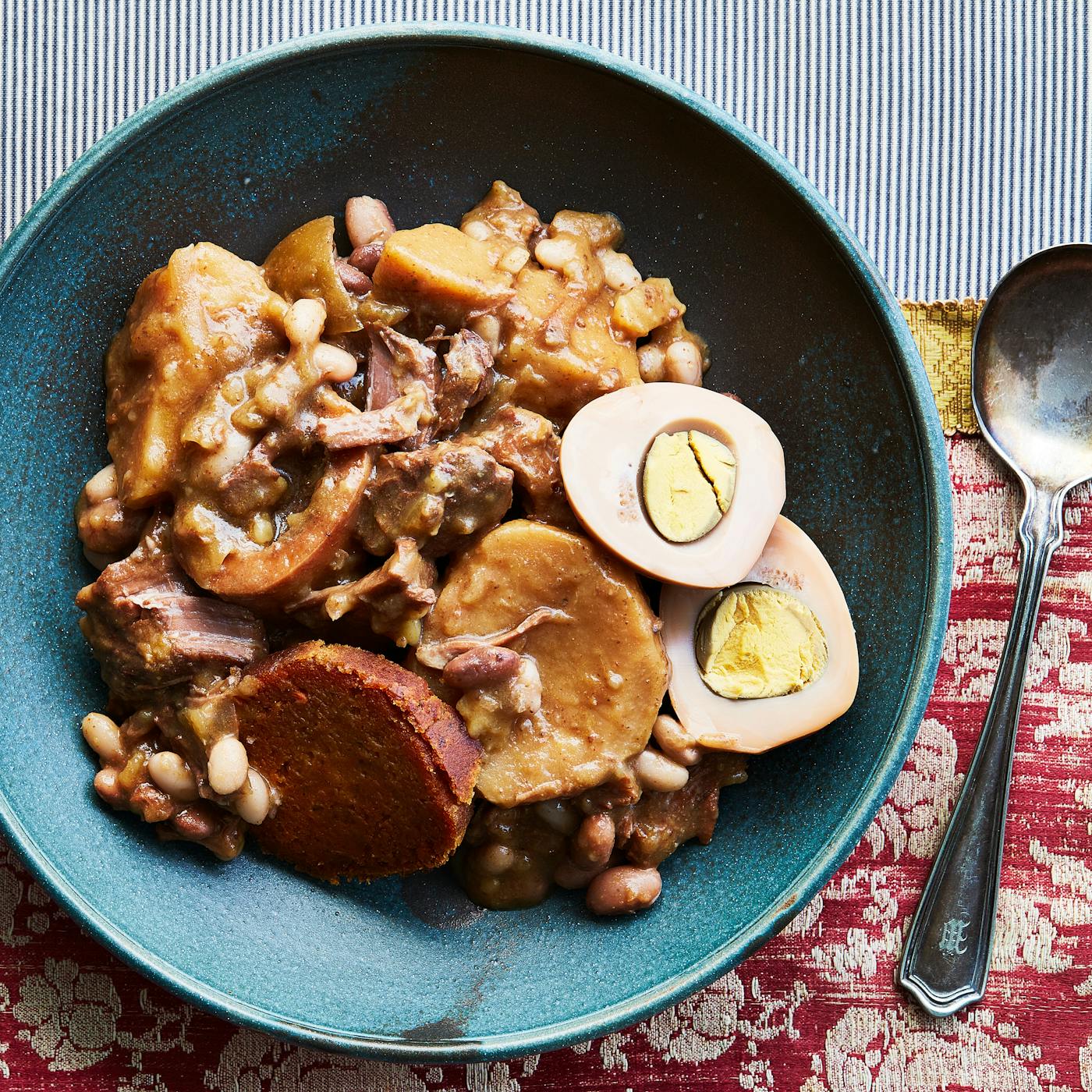 Cholent with Eggs and Kishke on red tablecloth.