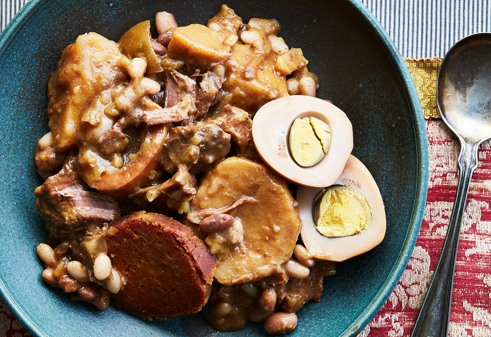 Cholent with Eggs and Kishke on red tablecloth.