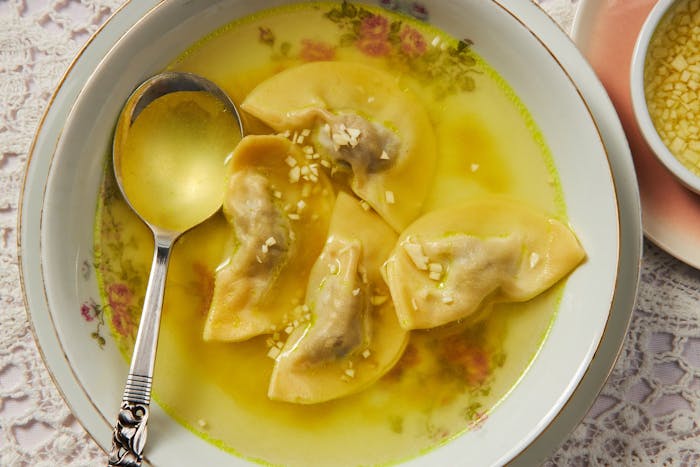 Dumpling soup with dish of minced garlic and broth.