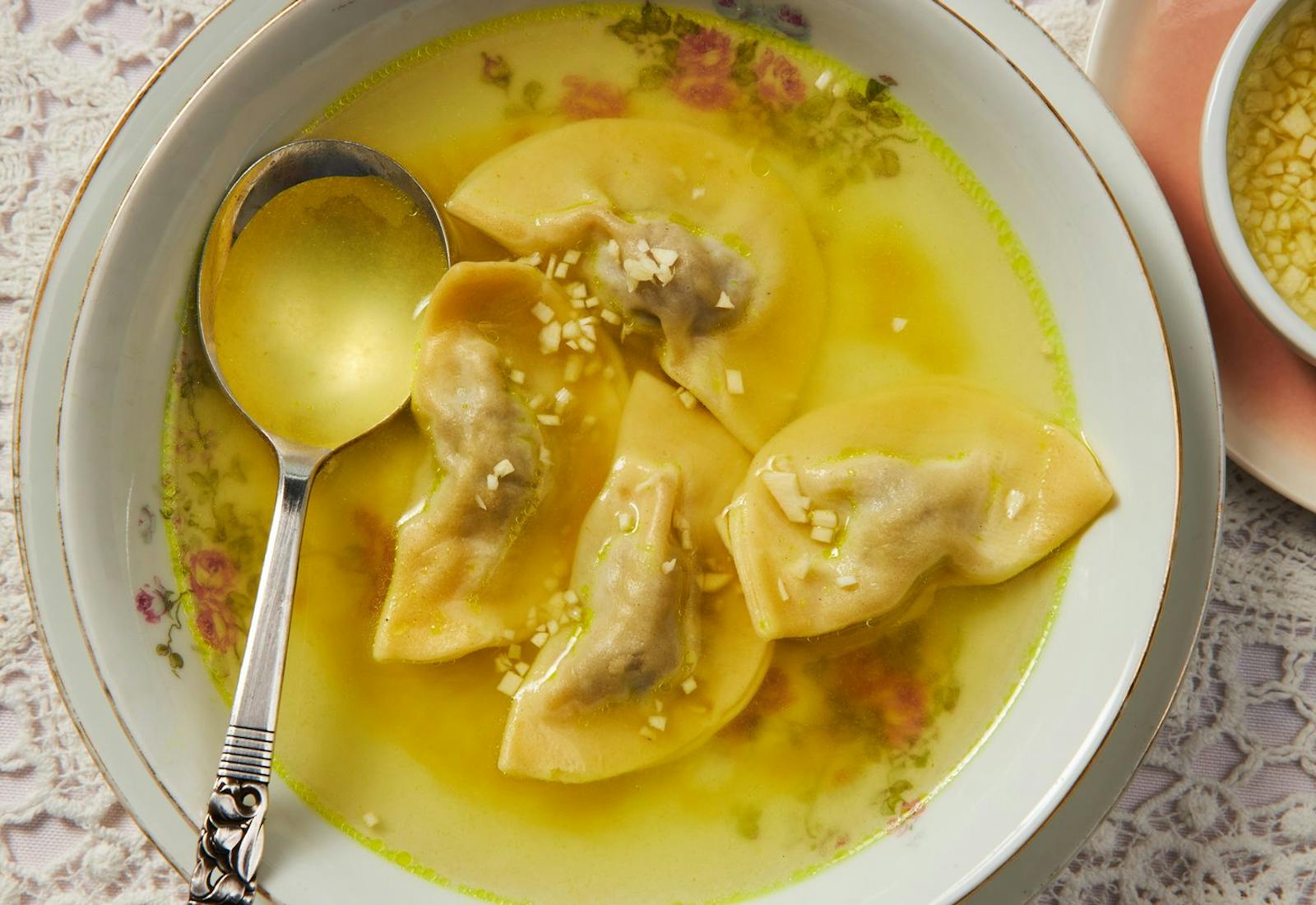 Dumpling soup with dish of minced garlic and broth.