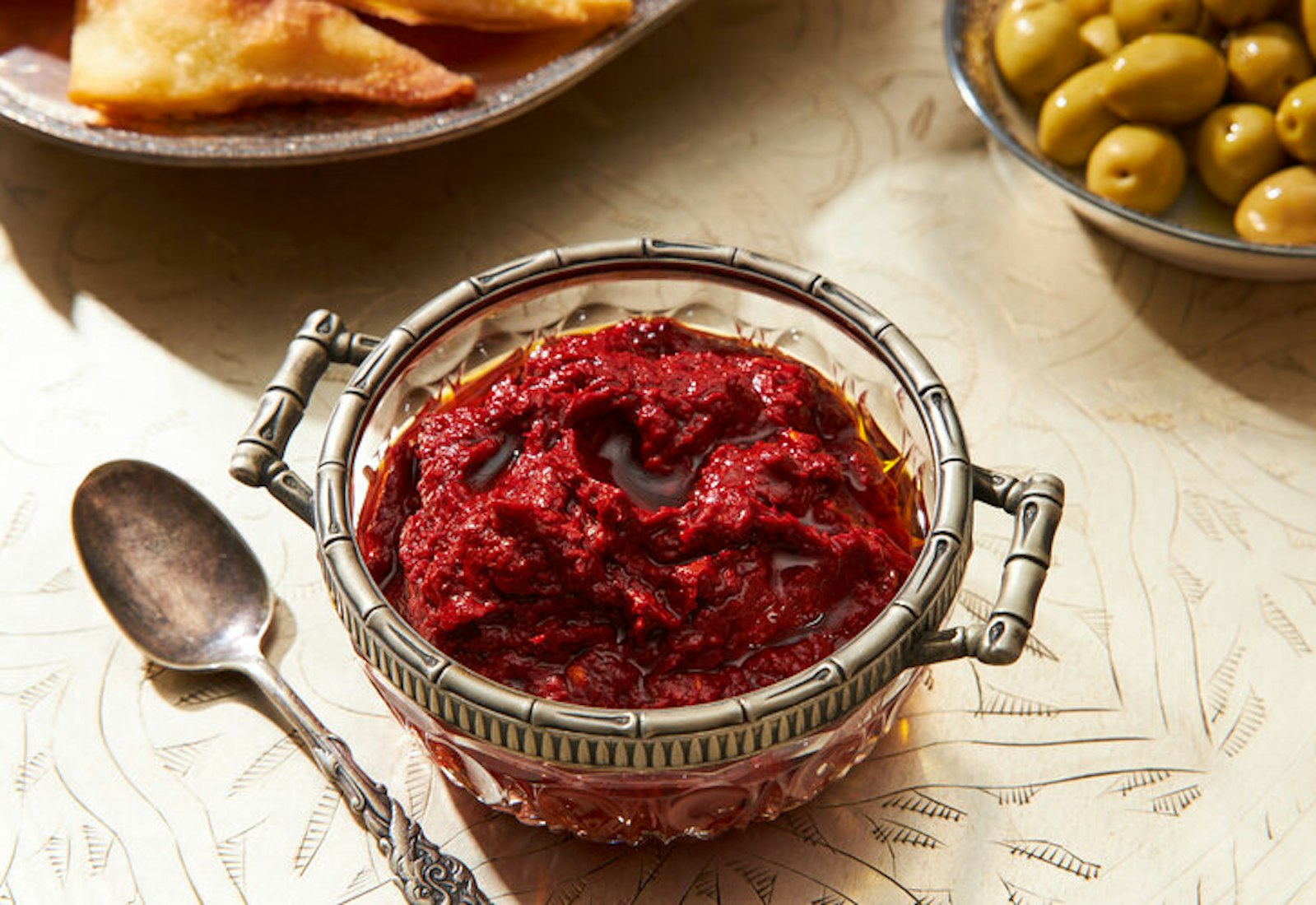 Harissa in a glass bowl, side of marinated olives.