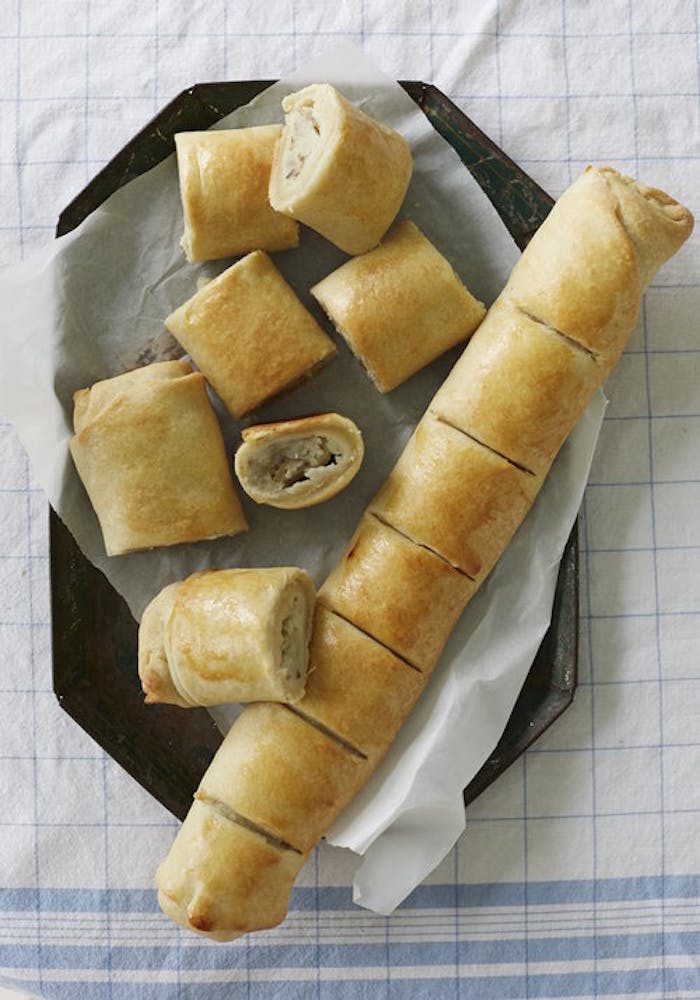 Sliced roasted garlic potato knish on parchment paper atop black plate.