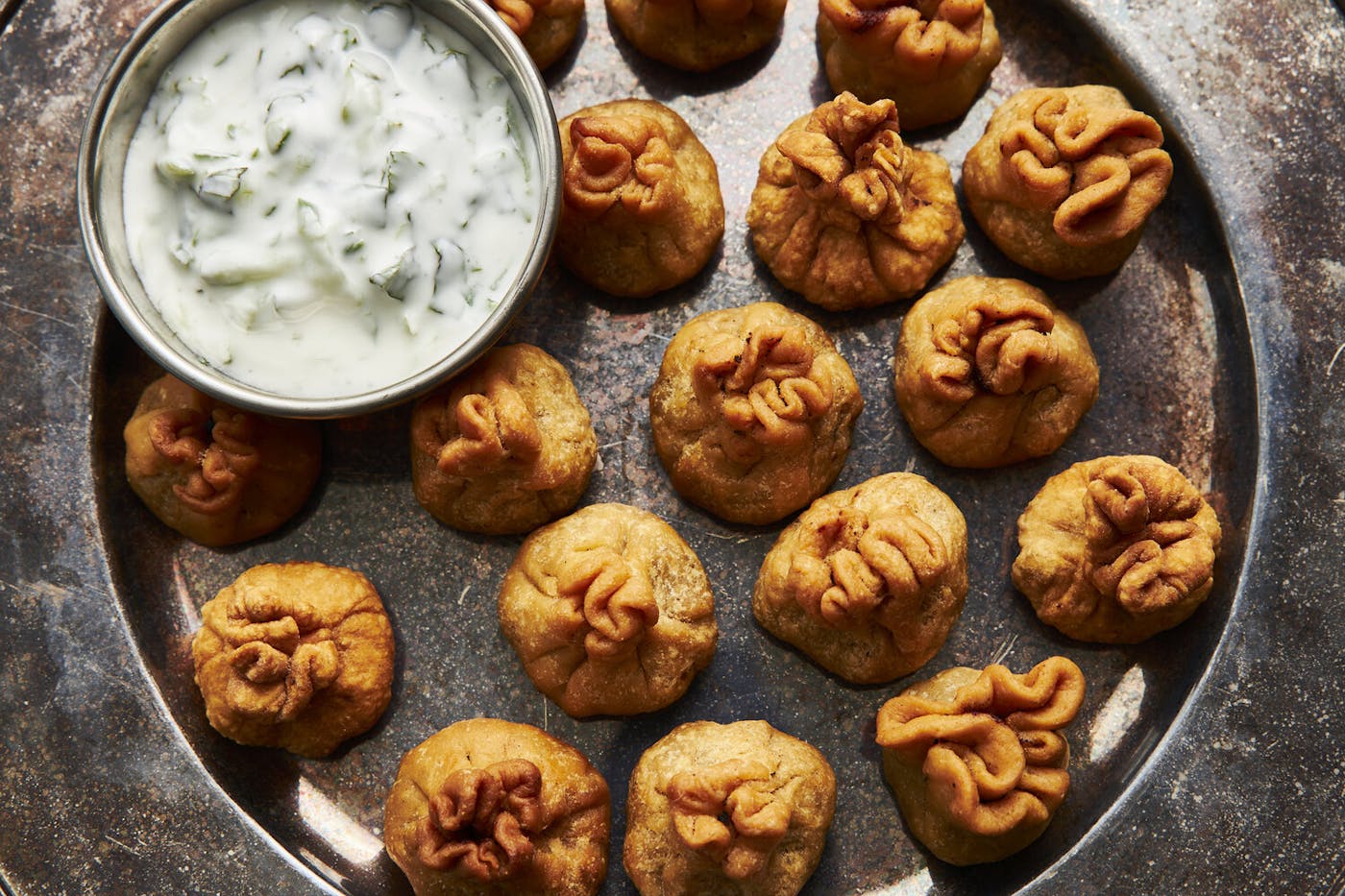 Kachori on bronze platter with bowl of mint raita.
