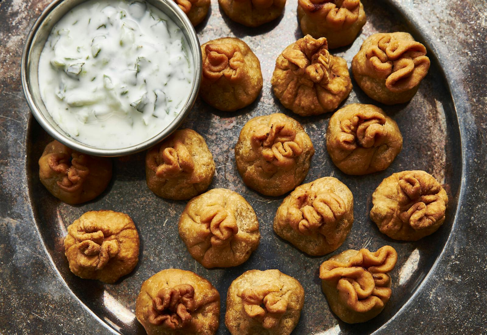 Kachori on bronze platter with bowl of mint raita.