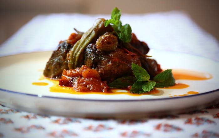 Egyptian short rib and okra stew with tomatoes and fragrant rice on white plate.