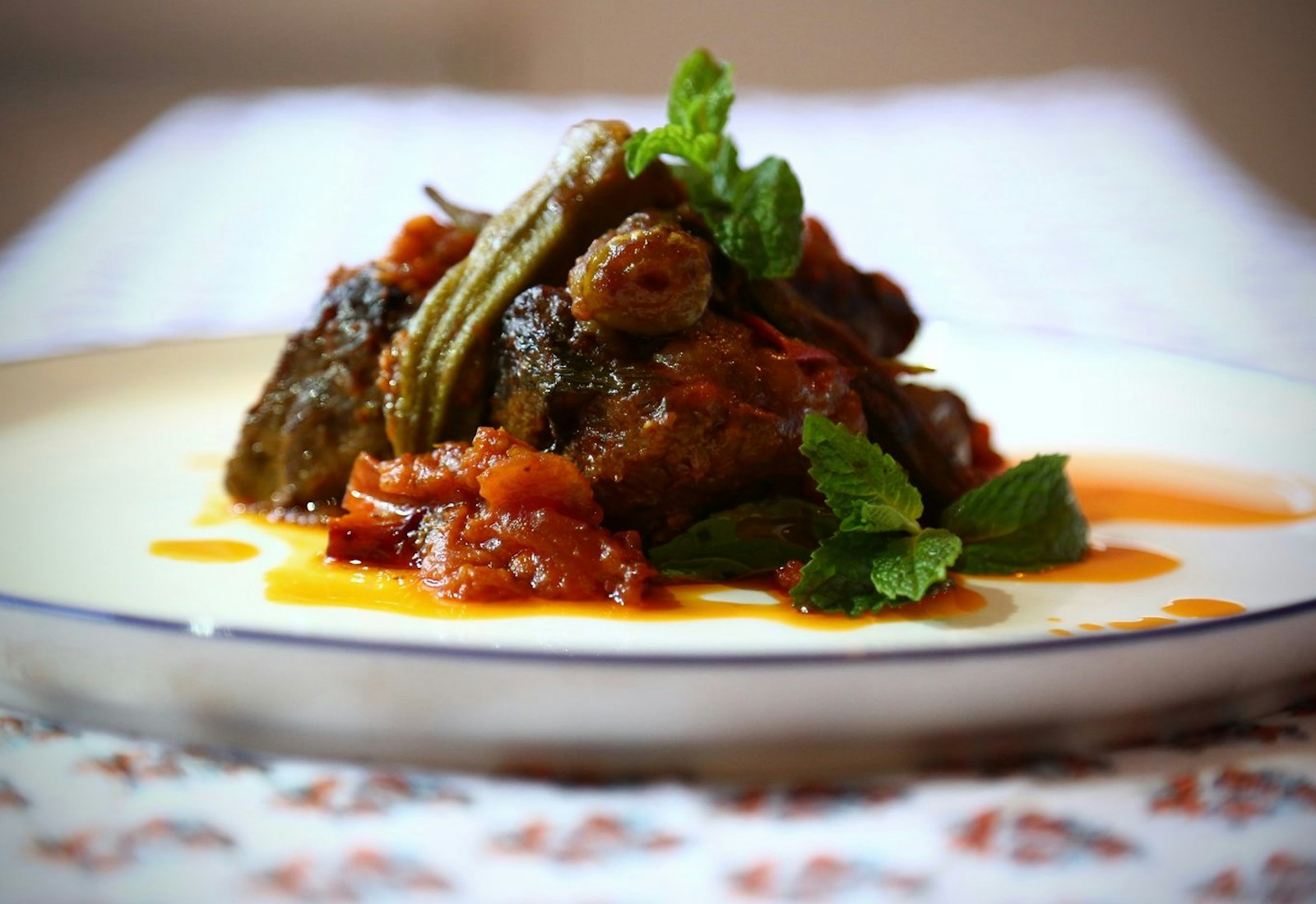 Egyptian short rib and okra stew with tomatoes and fragrant rice on white plate.