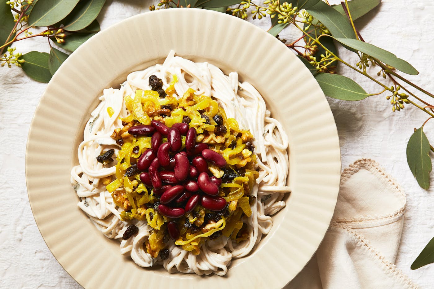 Ash reshteh garnished with kidney beans, onions, raisins and walnuts.