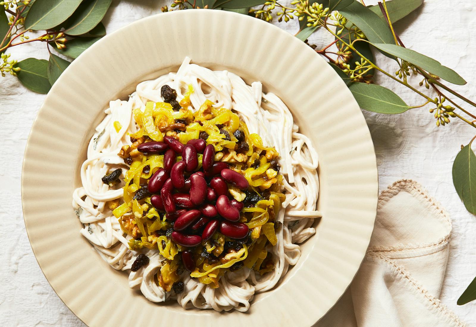 Ash reshteh garnished with kidney beans, onions, raisins and walnuts.