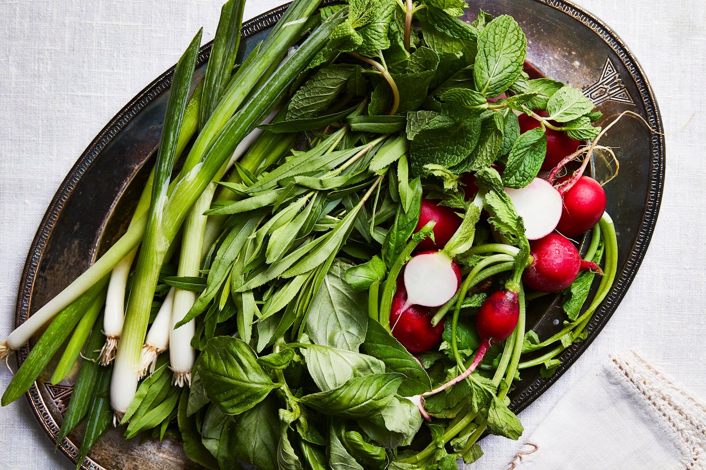 Plate of fresh herbs: scallions, basil, mint, and radishes.
