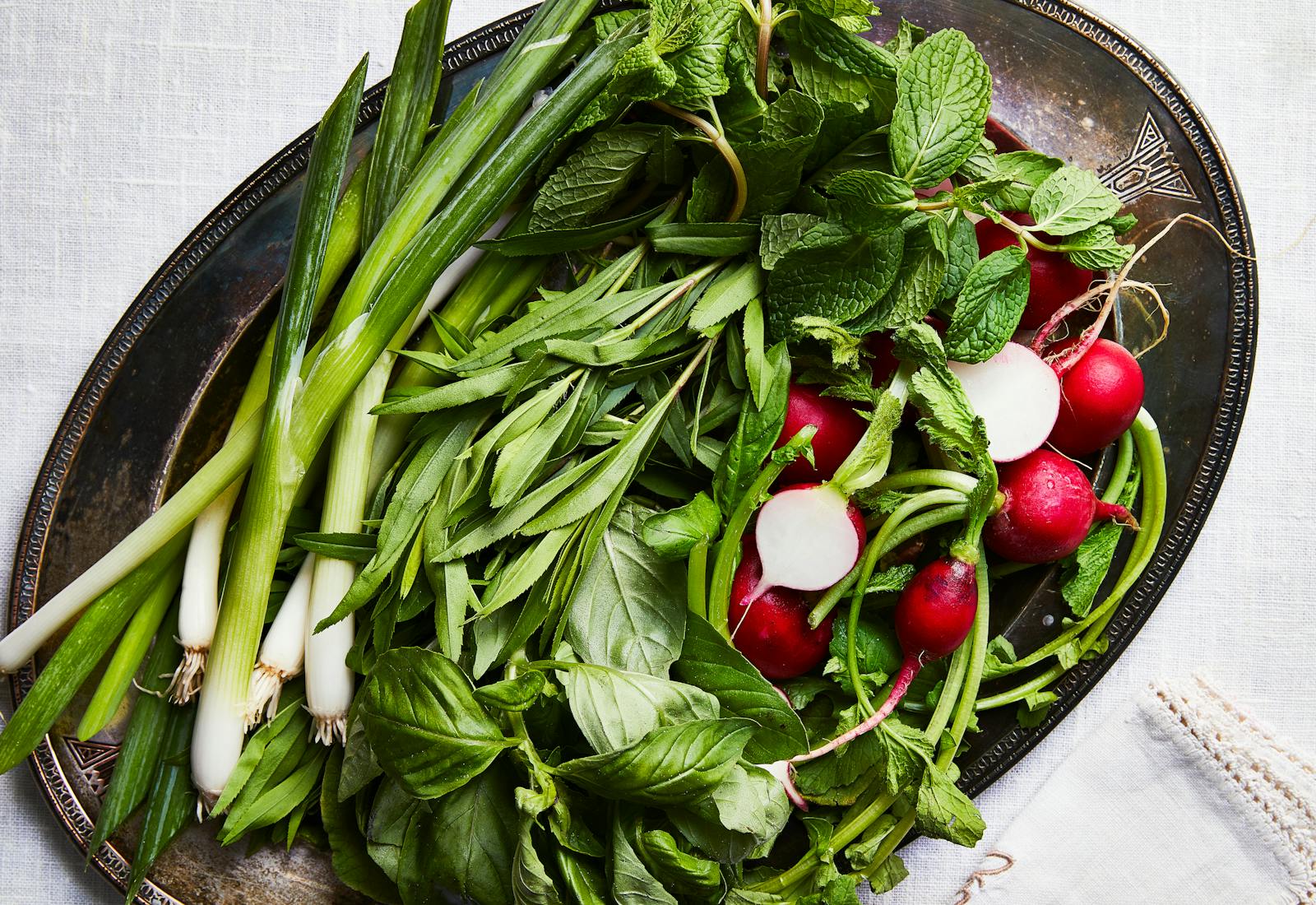 Plate of fresh herbs: scallions, basil, mint, and radishes.